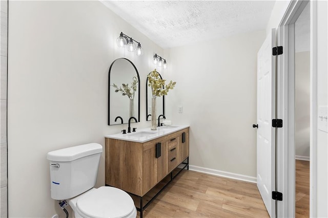 bathroom featuring toilet, vanity, a textured ceiling, and hardwood / wood-style flooring