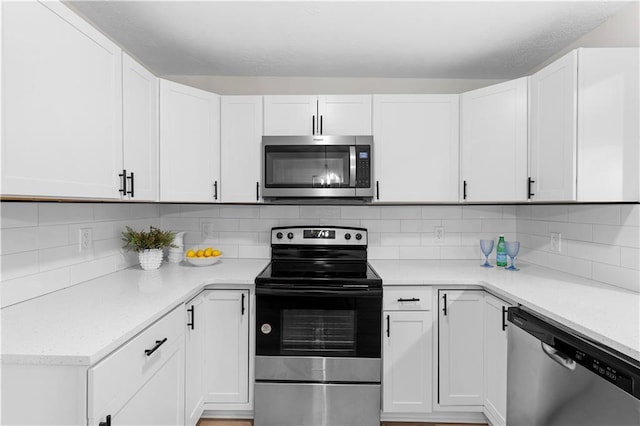 kitchen with stainless steel appliances, white cabinetry, and decorative backsplash