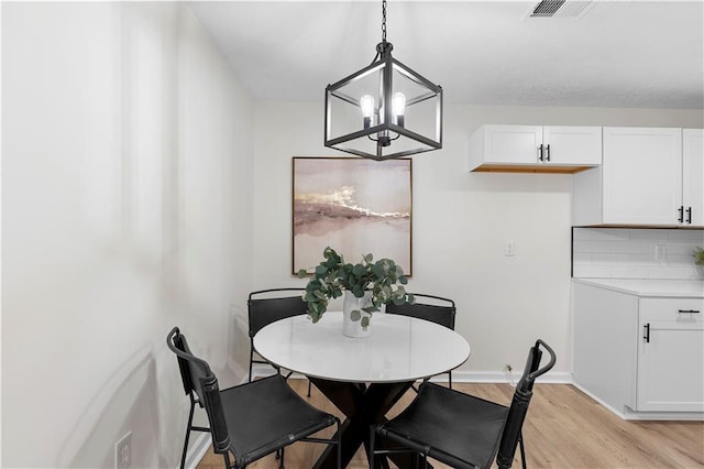 dining space featuring light hardwood / wood-style floors and an inviting chandelier