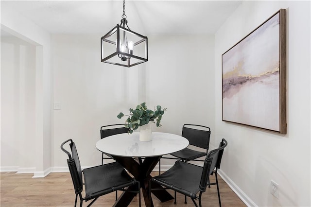 dining room with light hardwood / wood-style floors and a notable chandelier