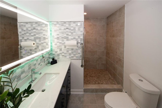 bathroom with toilet, a tile shower, vanity, and tile patterned flooring