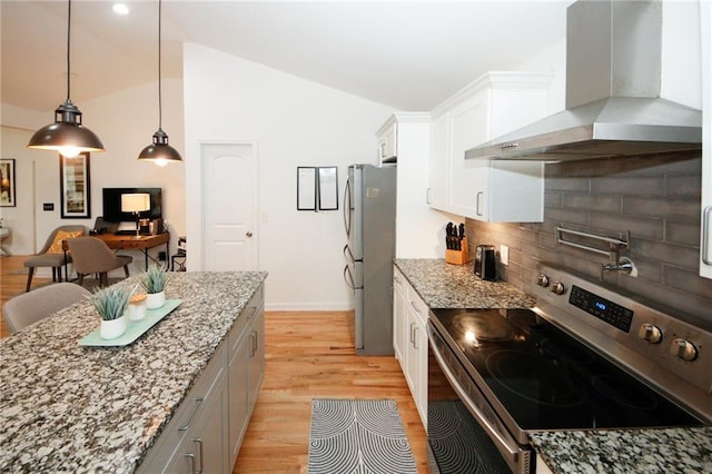 kitchen with stainless steel appliances, light stone countertops, wall chimney exhaust hood, white cabinetry, and lofted ceiling