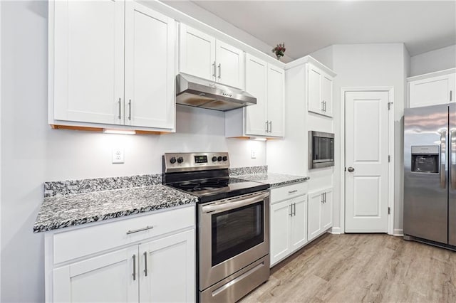 2646 Neighborhood Walk S, Villa Rica, GA 30180 - kitchen featuring under cabinet range hood, light stone counters, light wood finished floors, stainless steel appliances, and white cabinets
