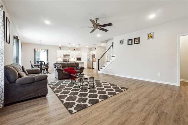 2646 Neighborhood Walk S, Villa Rica, GA 30180 - living room featuring baseboards, light wood-style floors, and ceiling fan with notable chandelier