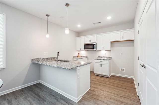 2646 Neighborhood Walk S, Villa Rica, GA 30180 - kitchen featuring light stone countertops, visible vents, a sink, stainless steel microwave, and light wood-type flooring