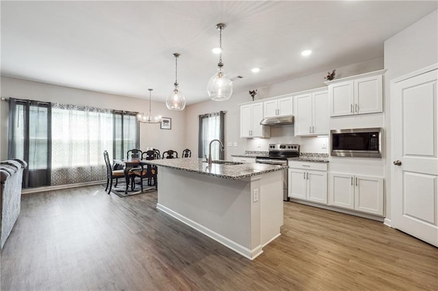 2646 Neighborhood Walk S, Villa Rica, GA 30180 - kitchen with under cabinet range hood, a sink, wood finished floors, white cabinets, and appliances with stainless steel finishes