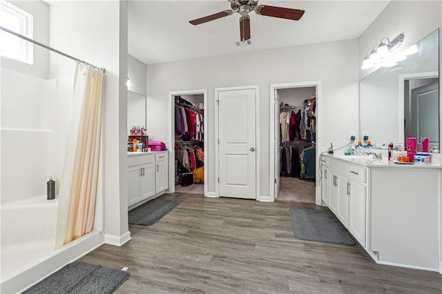 2646 Neighborhood Walk S, Villa Rica, GA 30180 - bathroom featuring wood finished floors, a ceiling fan, a shower with shower curtain, a walk in closet, and vanity