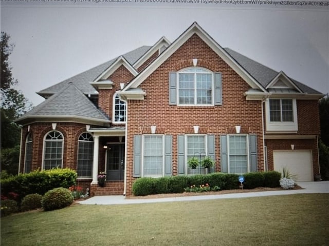 view of front of home featuring brick siding, driveway, a front lawn, and a garage