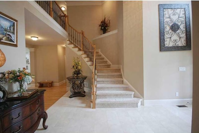 stairs with a high ceiling, baseboards, and visible vents