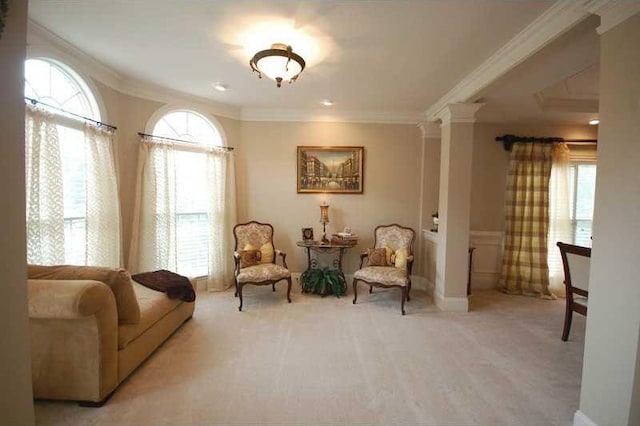 sitting room with plenty of natural light, carpet flooring, ornate columns, and ornamental molding