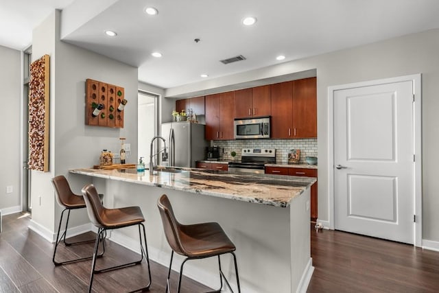 kitchen featuring stainless steel appliances, visible vents, a peninsula, and a breakfast bar area