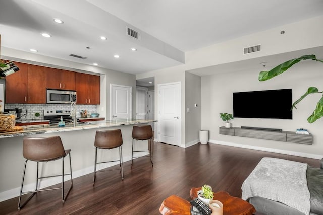 kitchen featuring open floor plan, stainless steel appliances, a kitchen bar, and visible vents