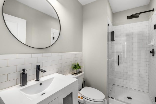 full bath with tile walls, a shower stall, toilet, and vanity