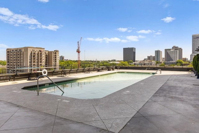 pool featuring a city view, fence, and a patio