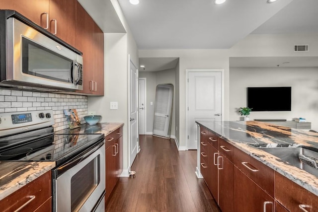 kitchen featuring dark wood-style floors, arched walkways, stainless steel appliances, visible vents, and decorative backsplash