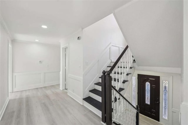 foyer featuring stairway, wood finished floors, recessed lighting, ornamental molding, and a decorative wall