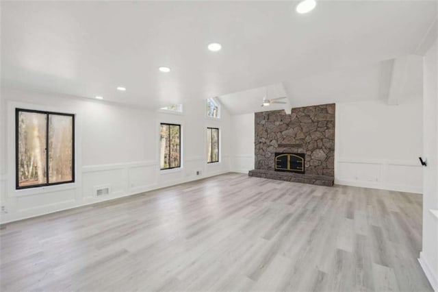 unfurnished living room featuring lofted ceiling, a decorative wall, a fireplace, and visible vents