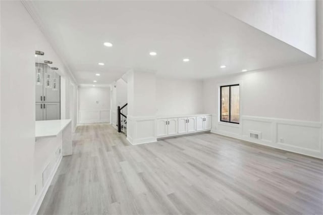 spare room featuring visible vents, a wainscoted wall, light wood-style flooring, recessed lighting, and a decorative wall