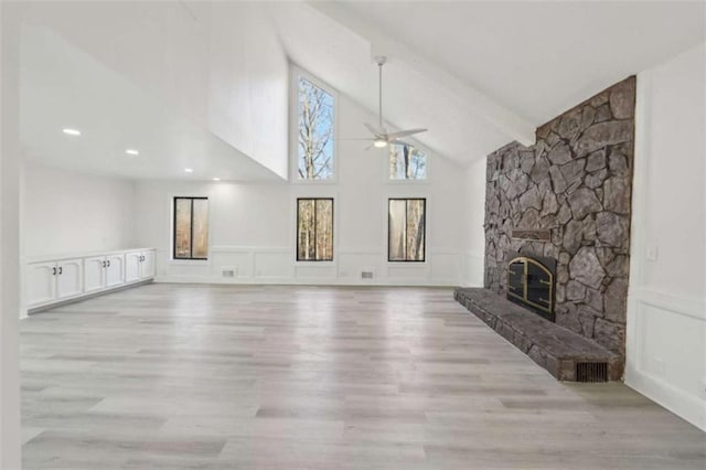 living room with plenty of natural light, a ceiling fan, a fireplace, and a decorative wall