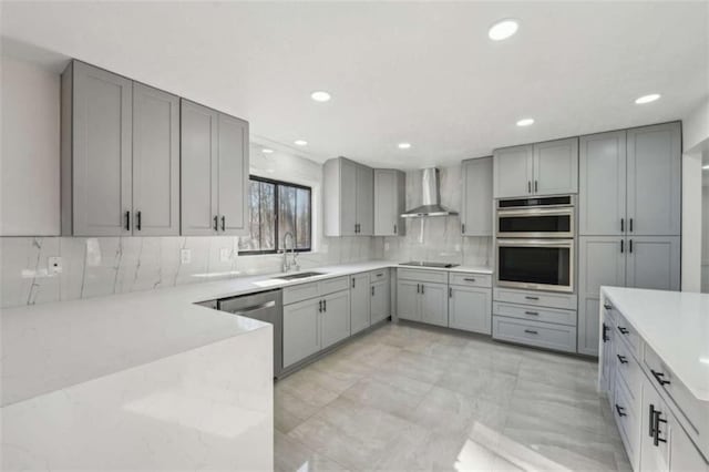 kitchen with a sink, wall chimney range hood, gray cabinetry, and stainless steel appliances