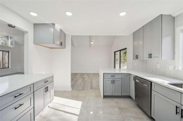 kitchen featuring gray cabinetry, light countertops, a peninsula, and stainless steel dishwasher