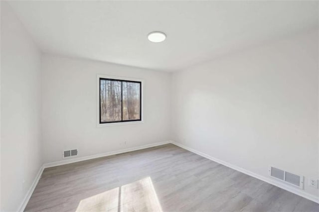 unfurnished room featuring wood finished floors, visible vents, and baseboards