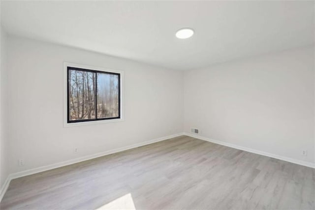 empty room with visible vents, baseboards, and wood finished floors