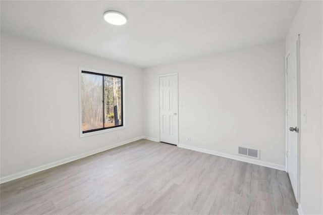 unfurnished room featuring wood finished floors, visible vents, and baseboards