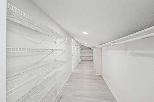 spacious closet with wood finished floors and vaulted ceiling