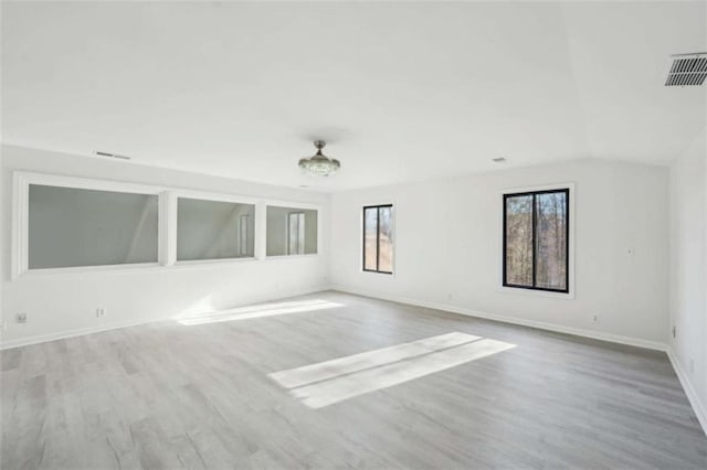 unfurnished room featuring vaulted ceiling, visible vents, baseboards, and wood finished floors