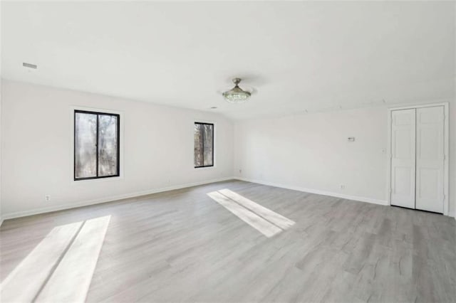 unfurnished room featuring visible vents, light wood-type flooring, and baseboards