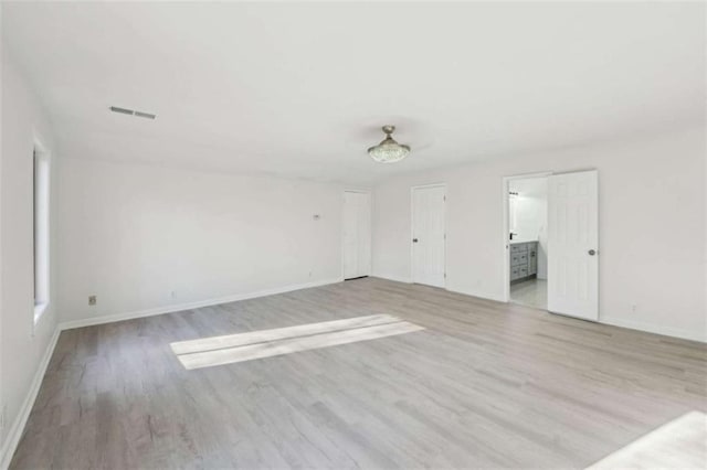 empty room with visible vents, baseboards, and wood finished floors