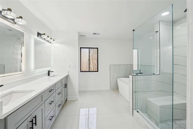 full bathroom featuring a marble finish shower, a freestanding tub, baseboards, and a sink