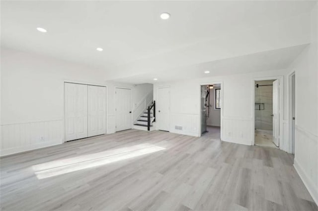 interior space with recessed lighting, a wainscoted wall, light wood-style flooring, and stairs