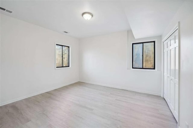 unfurnished room with baseboards, visible vents, and light wood finished floors