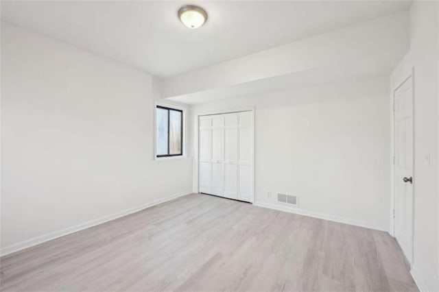 unfurnished bedroom with visible vents, baseboards, a closet, and wood finished floors