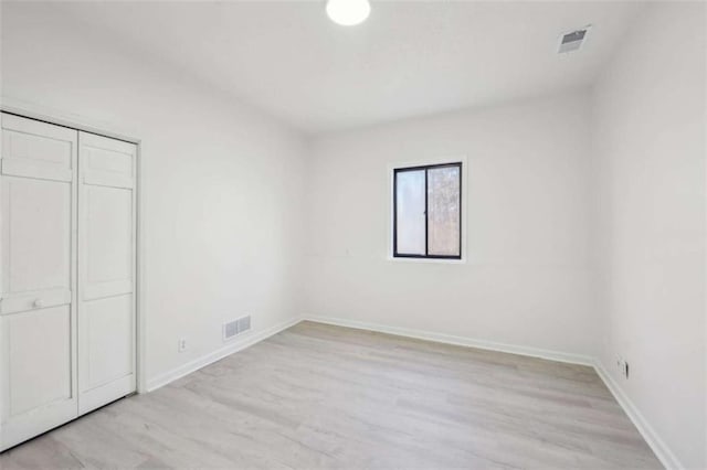 unfurnished bedroom with visible vents, baseboards, a closet, and light wood finished floors