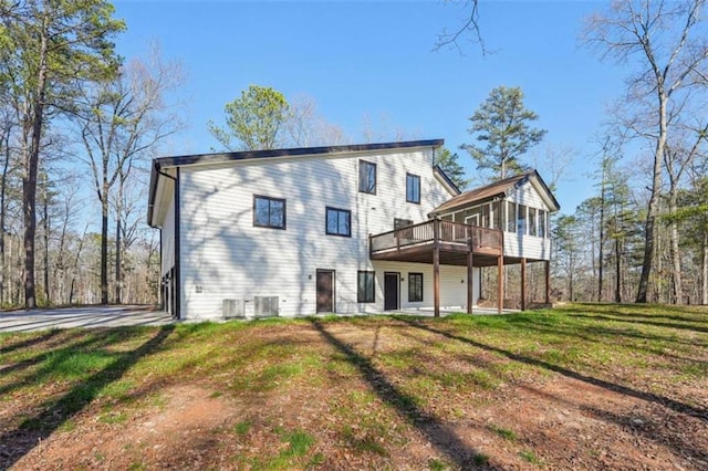 back of property featuring a deck, a lawn, and central AC