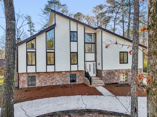 view of front of property featuring stone siding, a chimney, and entry steps