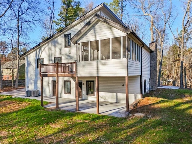 back of house featuring a lawn, a patio, a sunroom, central AC unit, and a chimney