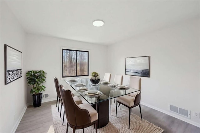 dining room featuring visible vents, baseboards, and wood finished floors