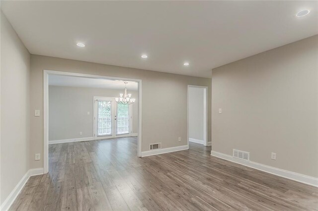 2682 Cavalier Dr, Decatur, GA 30034 - empty room with visible vents, baseboards, a notable chandelier, and wood finished floors