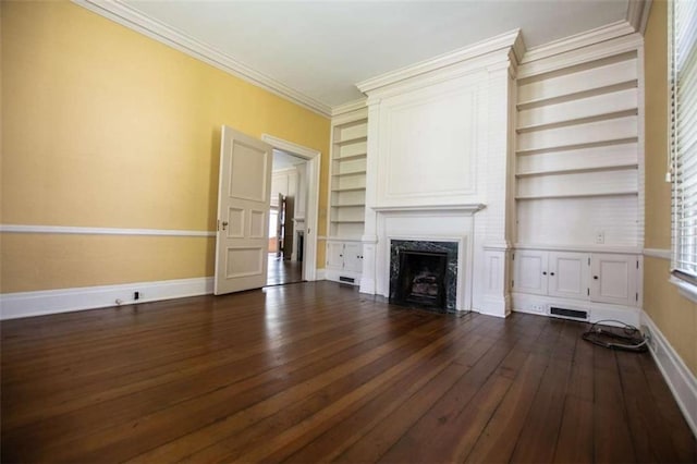 unfurnished living room with crown molding, dark hardwood / wood-style floors, a fireplace, and built in shelves