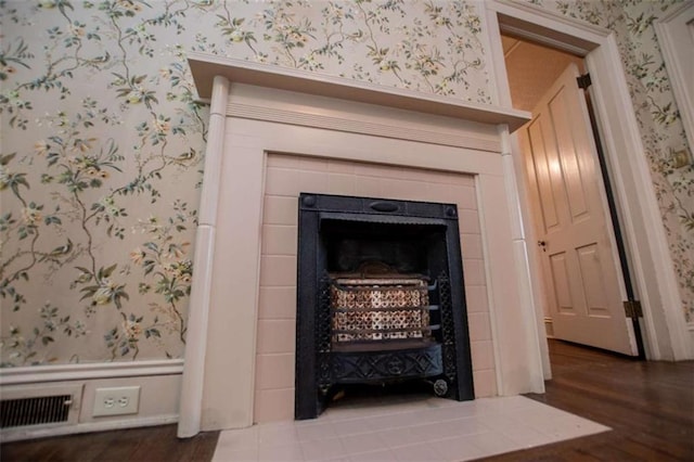 interior details with a tile fireplace and wood-type flooring