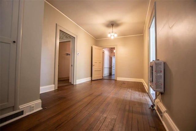 interior space with dark wood-type flooring, ornamental molding, heating unit, and a notable chandelier