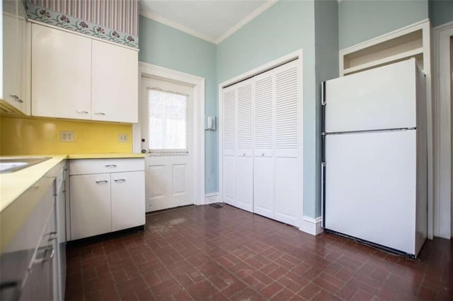 kitchen with white refrigerator, crown molding, sink, and white cabinets