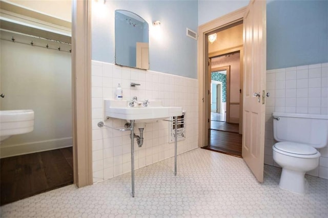 bathroom featuring tile walls and toilet