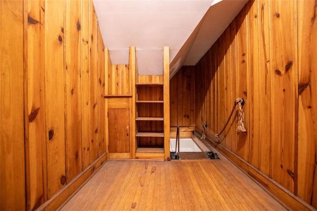 bonus room with wooden walls and light hardwood / wood-style flooring