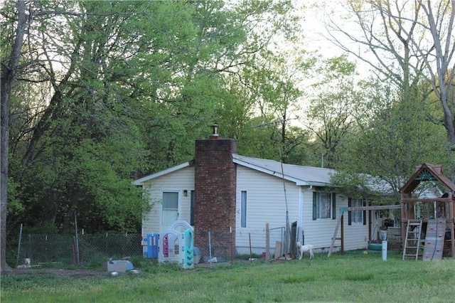 rear view of property with a lawn and a playground