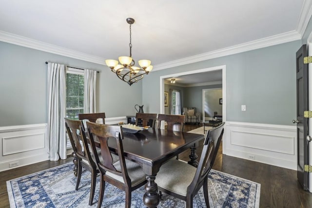 dining space with a chandelier, crown molding, dark wood-style flooring, and a wainscoted wall
